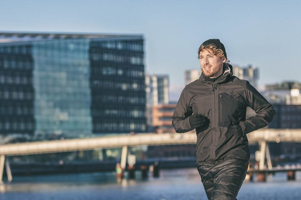 Winter running man cold weather sport clothing active athlete city urban living jogging outside on Europe street banner panoramic background. Copenhagen, Denmark.