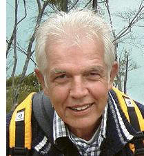 A man with white hair and a beard is smiling for the camera. He is wearing a blue and white striped shirt and a backpack. AI generated content